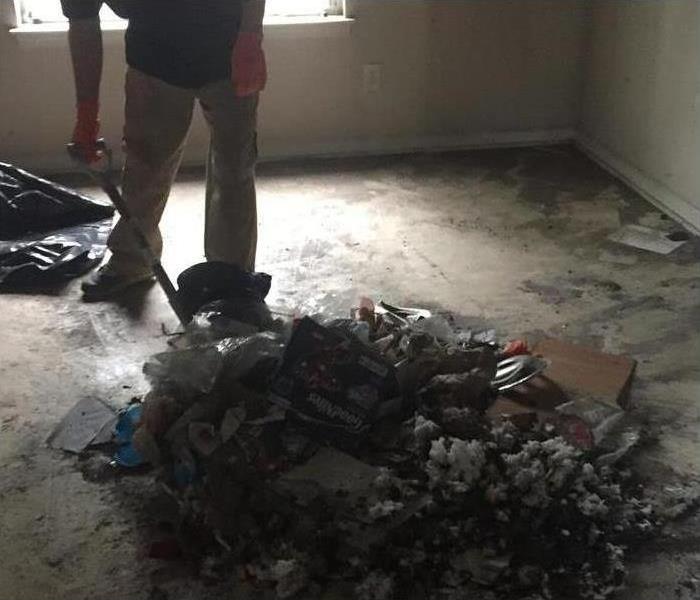 person cleaning up pile of trash from fire