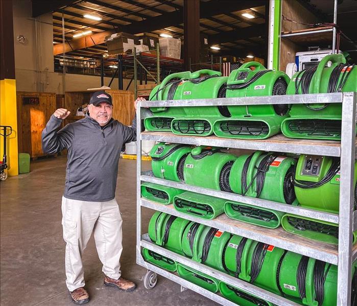 Servpro technician smiling while pushing a cart full of water damage drying fans