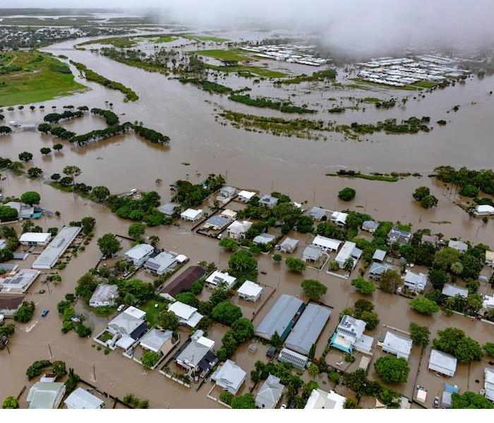 Birds-eye view of a residential area overtaken by floods, with submerged homes and water-covered streets.